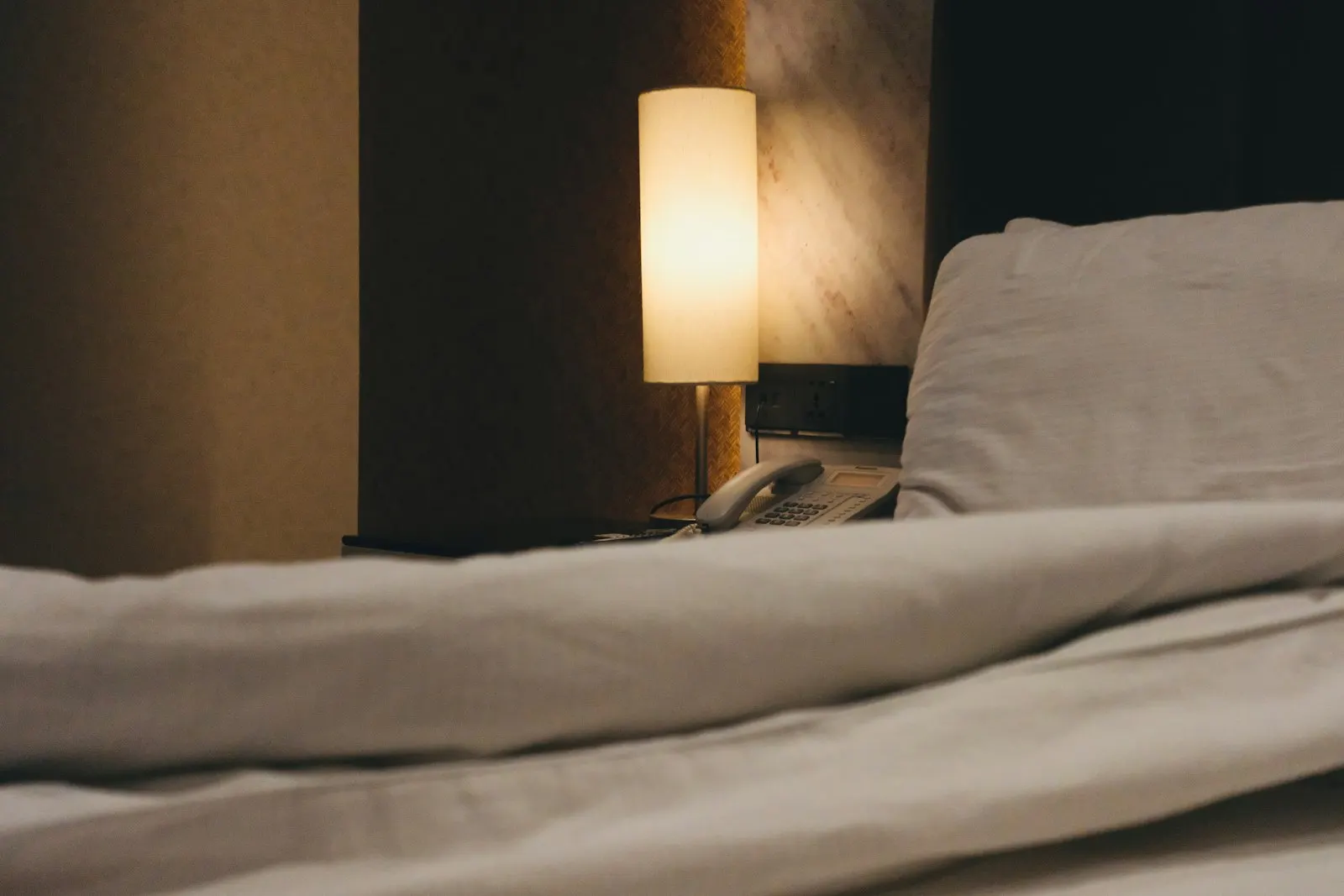 Nachttischlampe neben einem ungemachten Bett mit weißer Decke