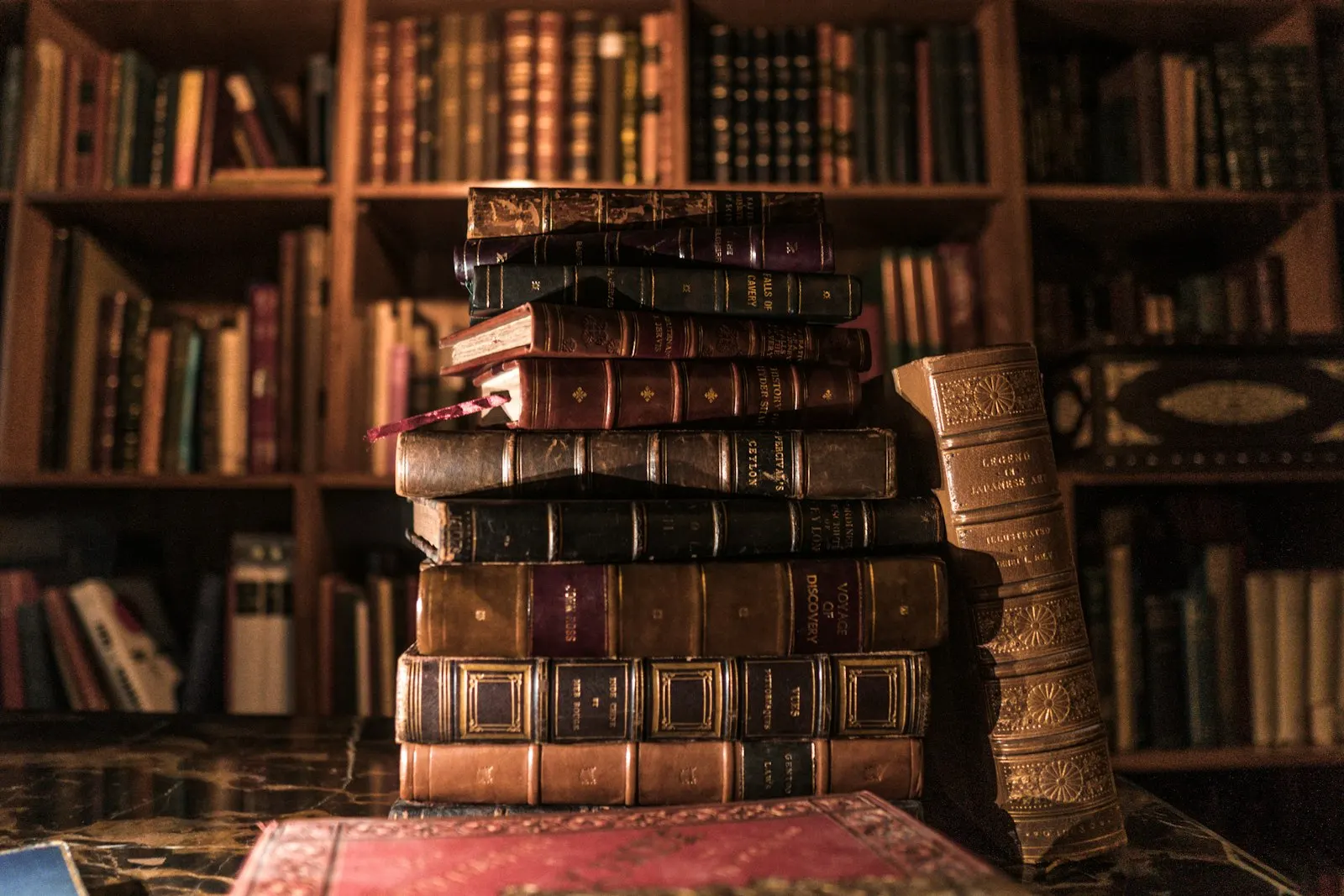 Stapel alter, in Leder gebundener Bücher vor einem Bücherregal